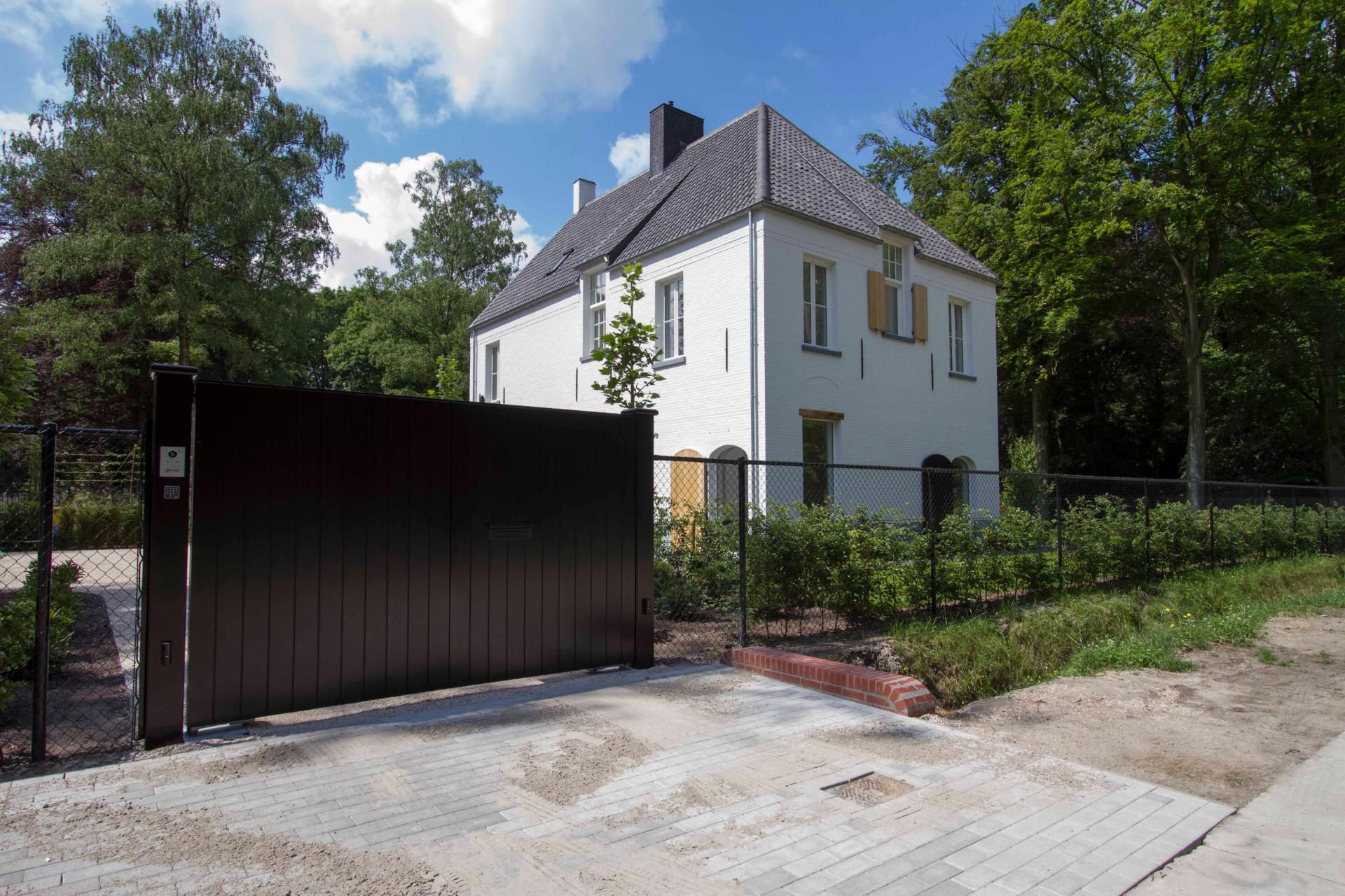 Donker geverfde poort aan een witte villa – Diba Outdoor